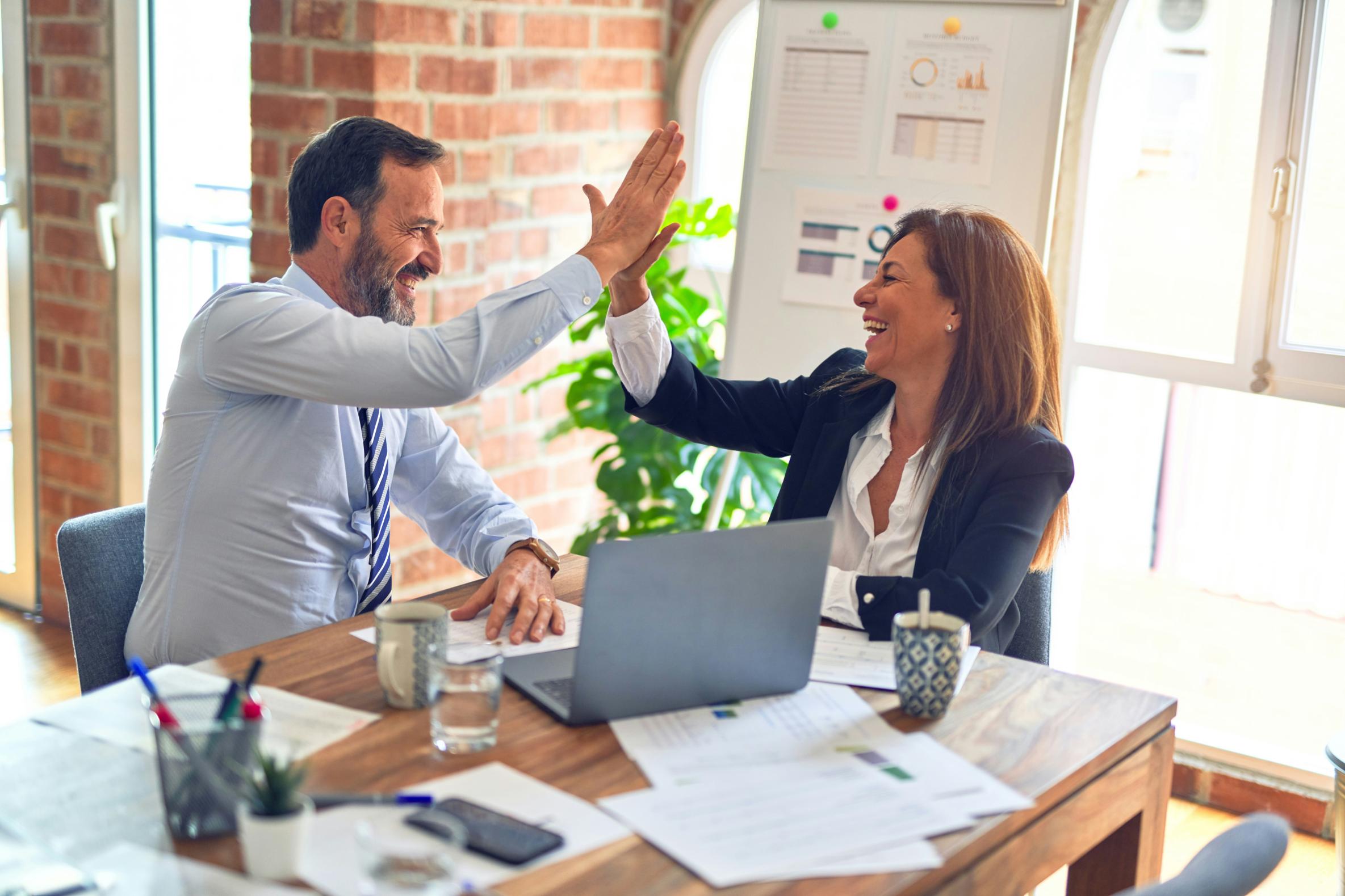 LSN Image of business persons high-fiving sitting at a desk